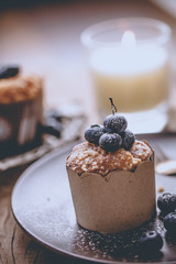 Blueberry muffin in a dish decorated with fresh blueberry and white candle on the table