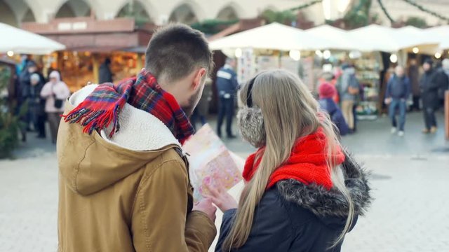 Couple standing at the christmas market and looking on the map, steadycam shot
