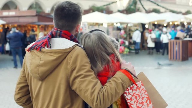 Lovely couple cuddling ath the christmas market in the town, steadycam shot
