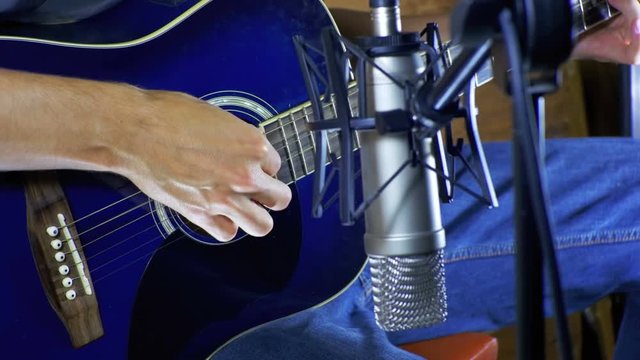 Musician Recording Acoustic Guitar in Microphone on the Home Studio