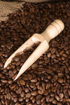 Wooden coffee spoon on background of coffee beans and sackcloth