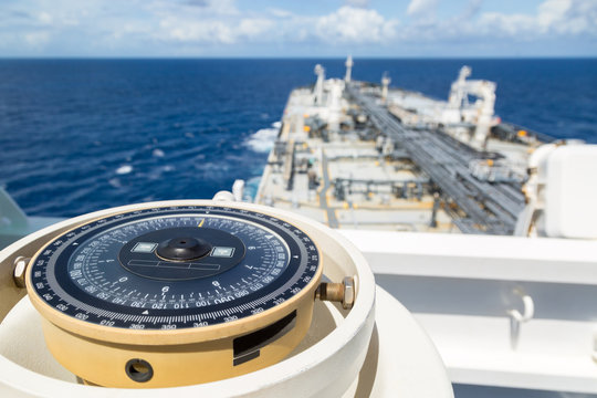 Compass aboard large ship on a blue summer sea.