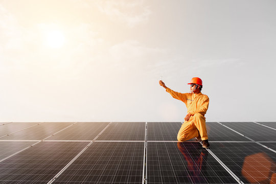 Engineers checking solar panels,Holding the bulb on the Solar Panel. Solar Energy ,The concepts of Clean Energy.