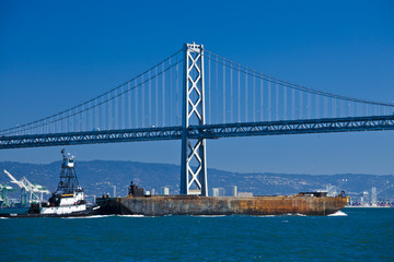 boat crossing under Oakland bridge