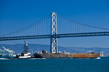 Fototapeta premium boat crossing under Oakland bridge