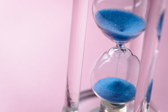 Close-up of hourglass with blue sand pouring