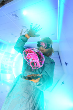 Boy in virtual reality headset interacting with digital floating human brain