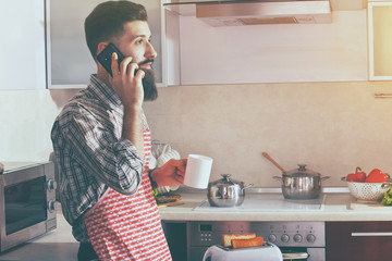 bearded man drinking morning coffee or tea and talking phone 