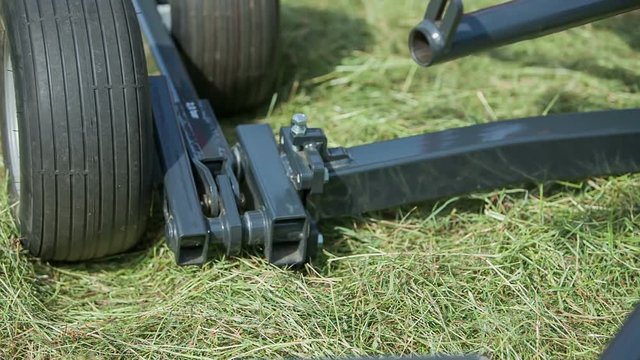 A farmer puts a missing piece back on a rotary hay rake and then a machinery will be ready to go.

