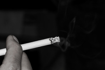 Macro shot of Man holding and smoking a cigarette. Dark black and white tone.