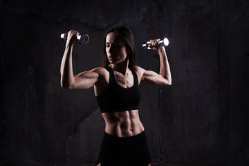 Active sportive athletic woman looking at bicep while pumping up