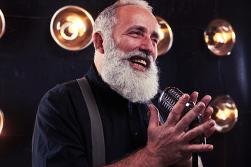 Delighted senior man singing in a retro silver studio microphone