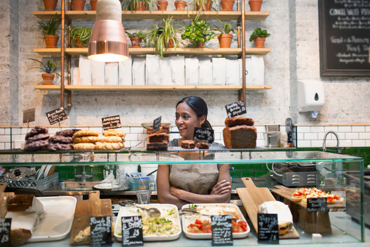 Waitress standing behind cafe display cabinet