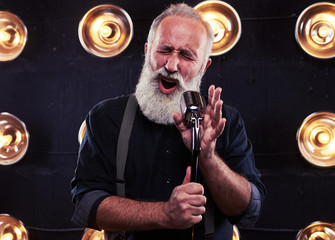 Impassioned man singing in a silver vintage microphone wearing d
