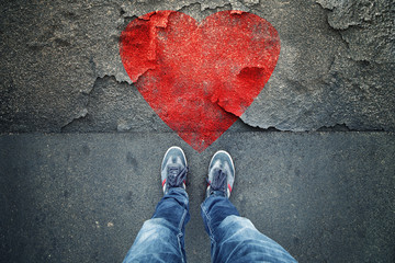 Point of view of a man standing on cracked damaged city asphalt floor with iilustrated broken heart...