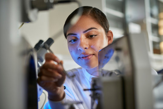 Scientists placing object on scientific equipment using tweezers