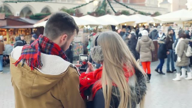 Boy doing photo of his girlfriend at the christmas market, steadycam shot
