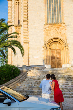 Rear view of young couple with convertible looking at map, Calvia, Majorca, Spain