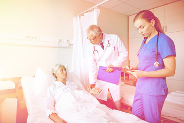 doctor and nurse visiting senior woman at hospital