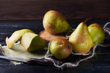 Fresh green pears and knife on a rustic background on a napkin. Dark shot