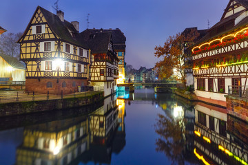 Traditional Alsatian half-timbered houses with mirror reflections in Petite France during twilight blue hour decorated and illuminated at christmas time, Strasbourg, Alsace, France