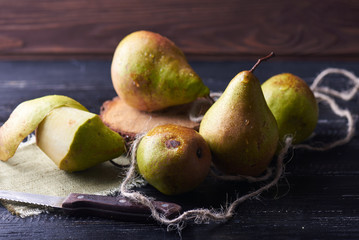 Fototapeta na wymiar Fresh green pears and knife on a rustic background on a napkin. Vertical shot