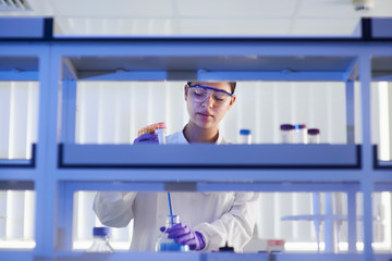 Scientist in laboratory using electronic pipette