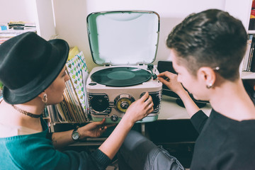Over shoulder view of two young women playing vinyl on vintage turntable