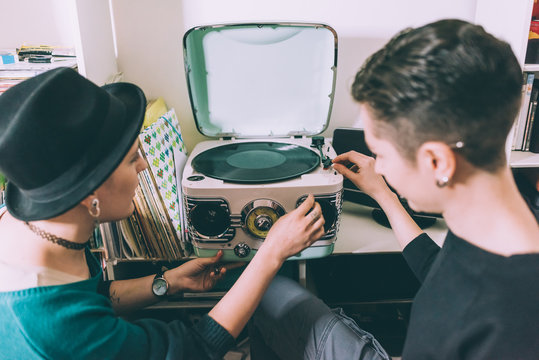 Over shoulder view of two young women playing vinyl on vintage turntable