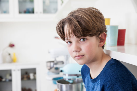 Portrait of boy sitting on kitchen work surface