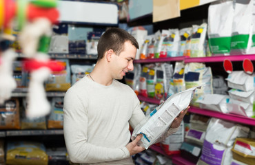 Portrait of  guy selecting vet food in petshop