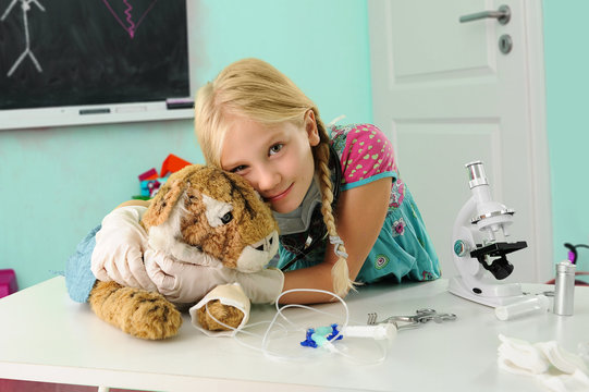 Portrait of girl pretending to be vet hugging toy tiger with intravenous drip