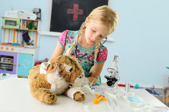 Girl pretending to be vet examining toy tiger using stethoscope