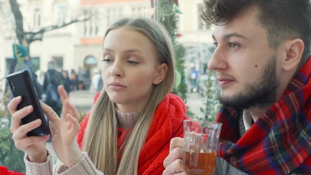 Girl browsing internet on smartphone and talking with her boyfriend, steadycam shot
