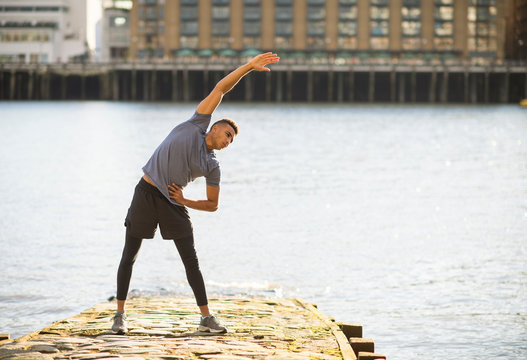 Man stretching on pier, Wapping, London, UK