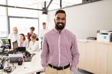 happy indian man over creative team in office