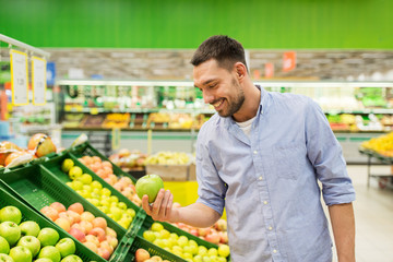 happy man buying green apples at grocery store