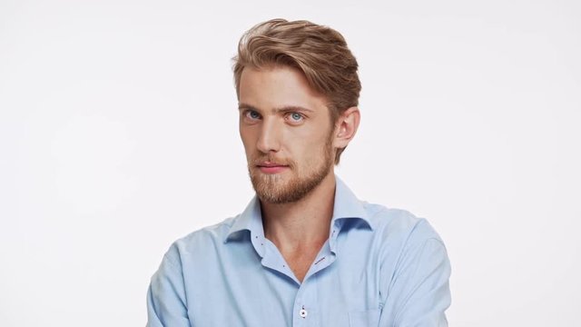Sexy Caucasian bearded male with blue eyes and brown beard ogles and touching hair on white background in slowmotion
