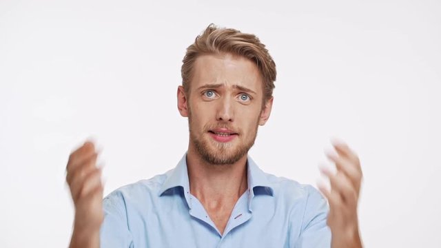 Disappointed Caucasian male with blue eyes and brown beard asking why on white background in slowmotion