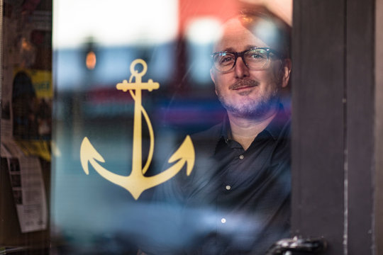 Portrait of barman looking through public house window, Brooklyn, New York, USA