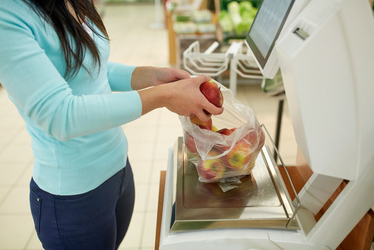 Woman Weighing Apples On Scale At Grocery Store