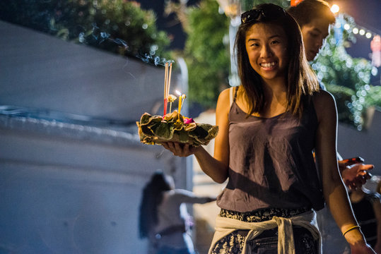 Young woman by Ping River in Chiang Mai during Loy Krathong Lantern Festival, releasing floating lantern down the Ping River, Chiang Mai, Thailand