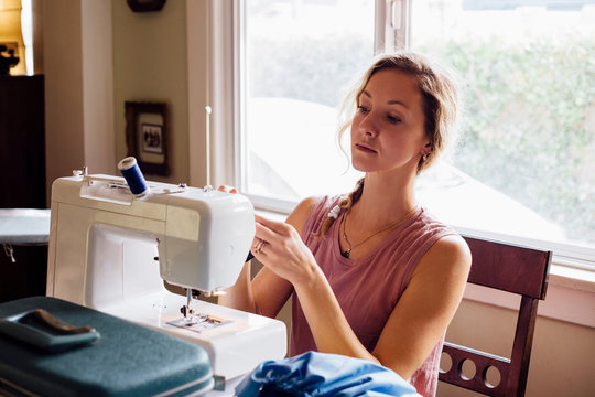 Woman threading sewing machine