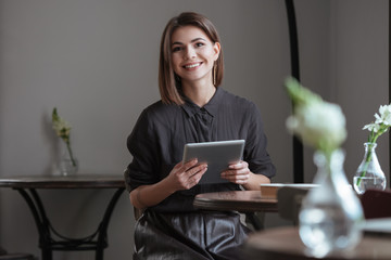 Beautiful lady sitting near window while using tablet computer.