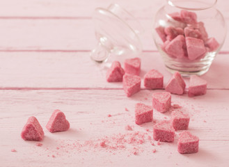 Granulated pink sugar  in the shape of heart on a wooden backgro