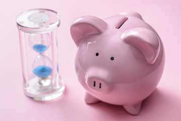 Piggy bank near classic hourglass with blue sand