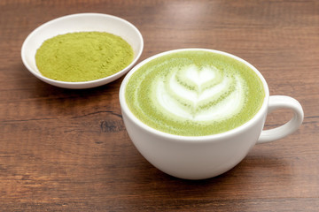 reen tea / Matcha latte in a cup with matcha powder on the wooden table
