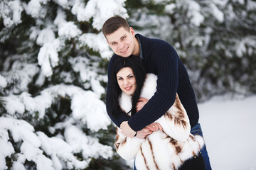 happy loving couple walking in snowy winter forest. Outdoor seasonal activities. Lifestyle capture.