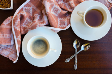 Cup  of black tea and cup of coffee with teaspoons and napkin on wooden background. Common...