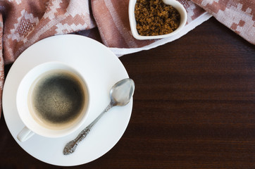 Cup of black coffee with coffee spoon ,brown sugar and vintage napkin on wooden background. Copy...